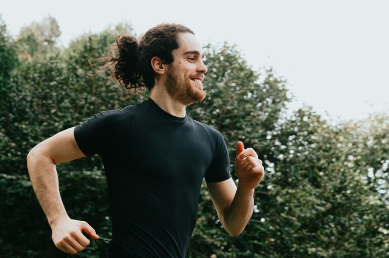 Um homem com rabo de cavalo em um parque aprendendo a como começar a correr